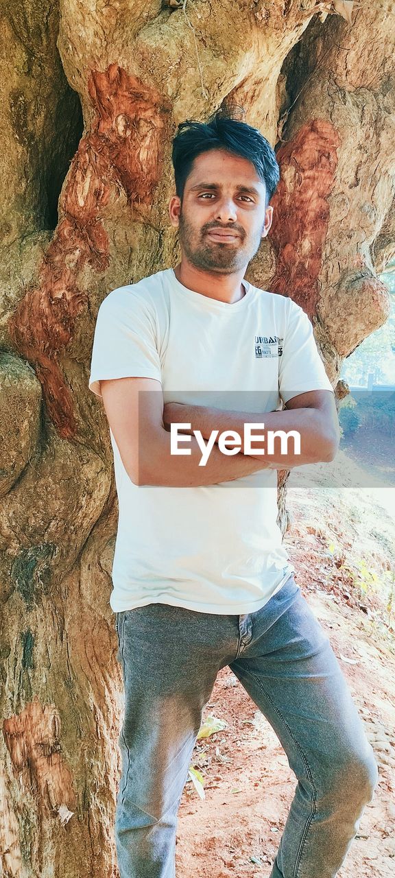 one person, portrait, looking at camera, men, adult, casual clothing, rock, leisure activity, front view, smiling, nature, day, full length, young adult, standing, lifestyles, cave, geology, outdoors, person, land, rock formation, three quarter length, mature adult, adventure, rock climbing, emotion, happiness