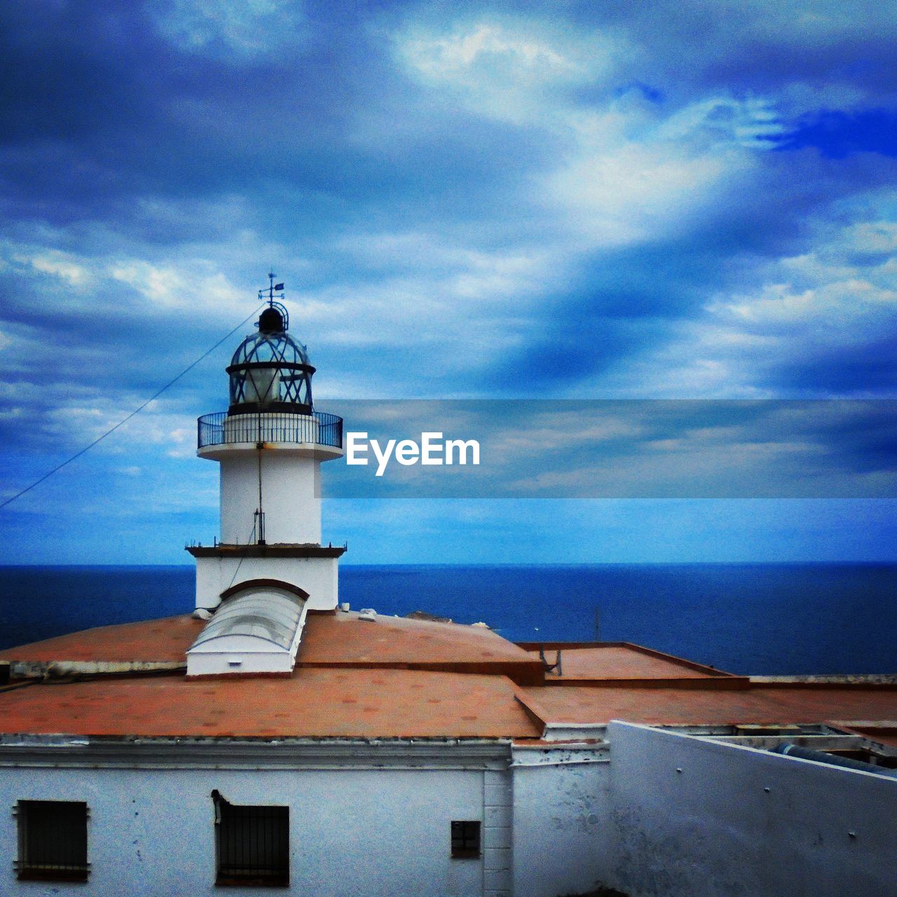 Lookout tower by sea against cloudy sky