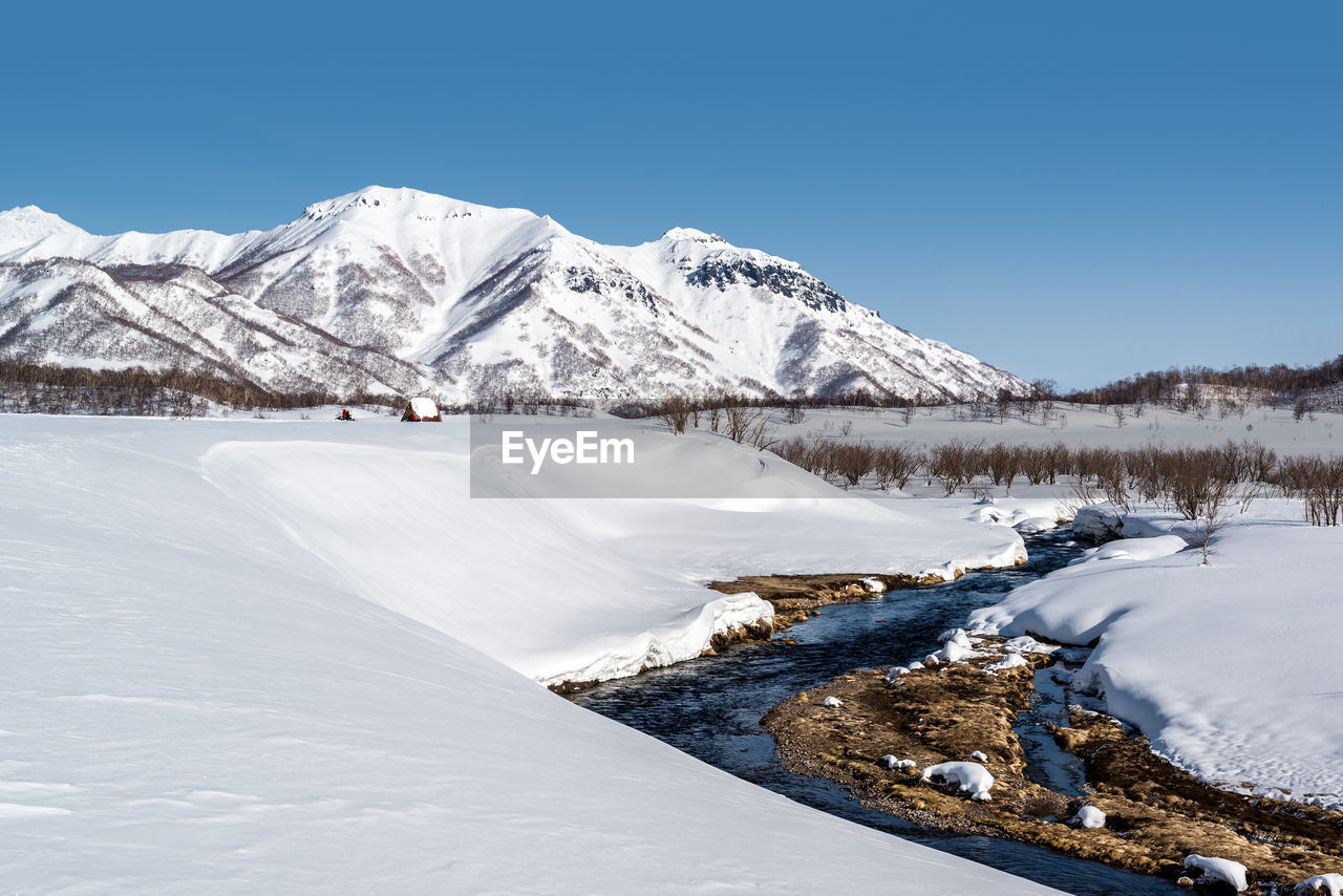 Scenic view of frozen lake against clear blue sky