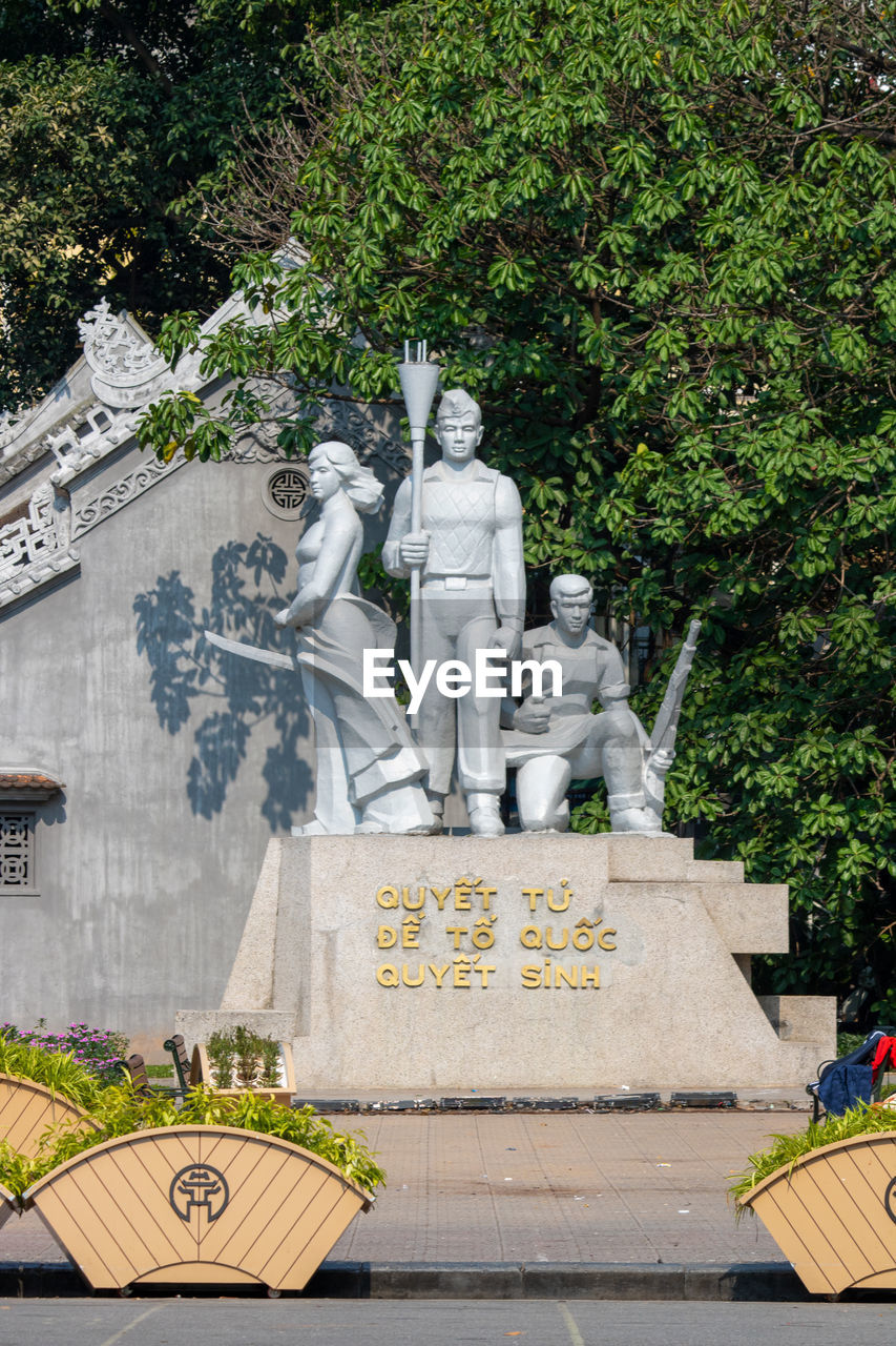 STATUE AGAINST TREE AND PLANTS