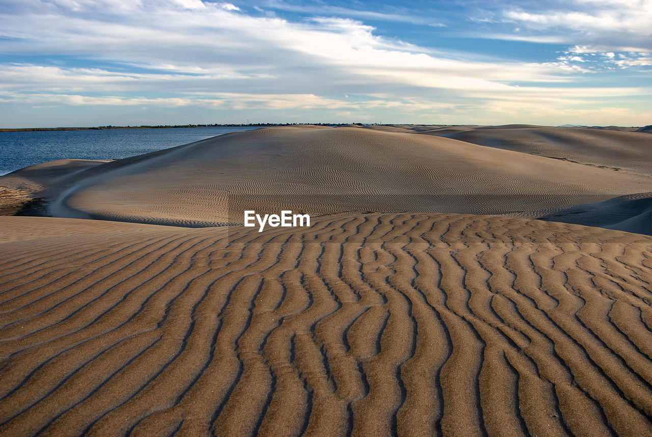 Scenic view of sand dune at beach against sky