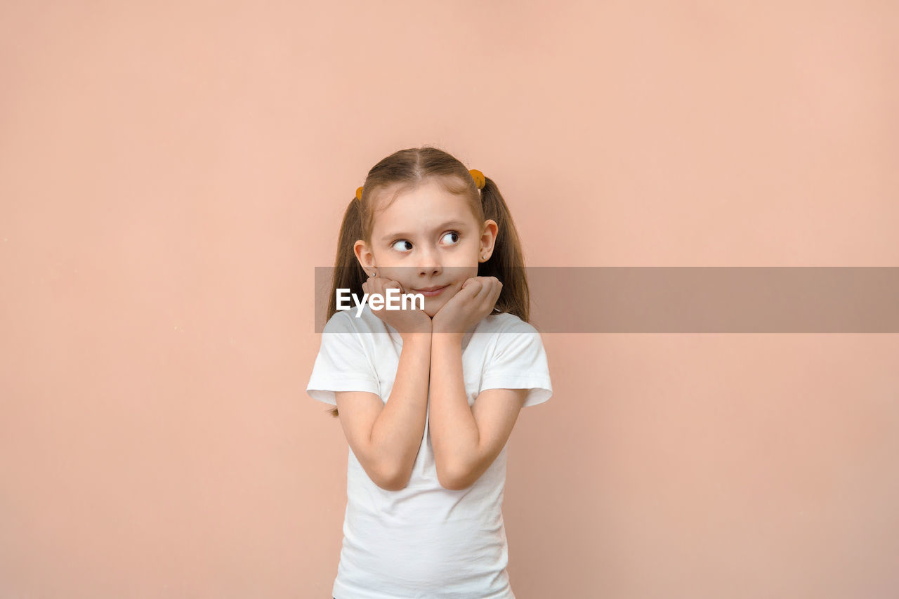 portrait of cute girl standing against wall