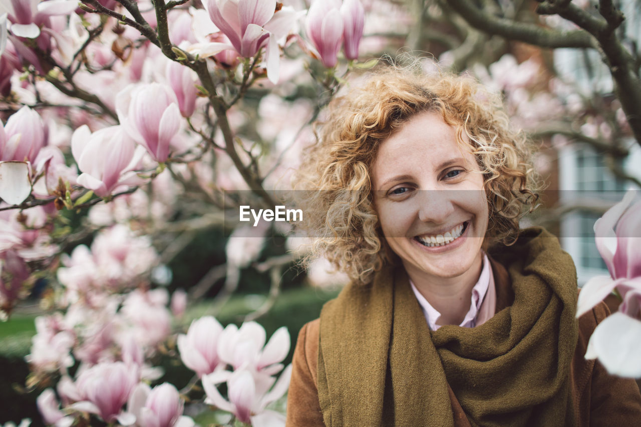 PORTRAIT OF HAPPY WOMAN WITH PINK FLOWER