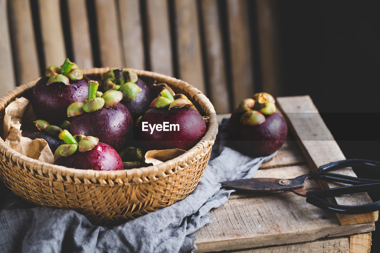 Close-up of purple mangosteen in basket on table