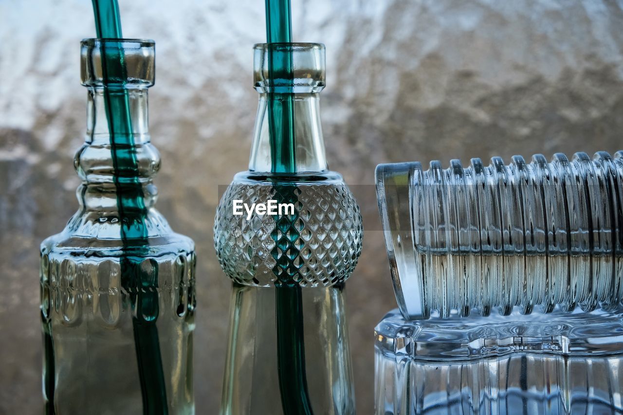 glass, no people, bottle, blue, container, focus on foreground, drinkware, food and drink, close-up, household equipment, lighting, indoors, group of objects