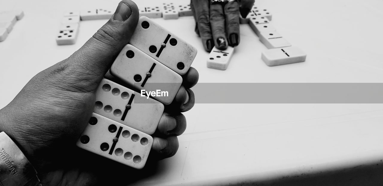 Cropped hands of friends playing dominoes at table