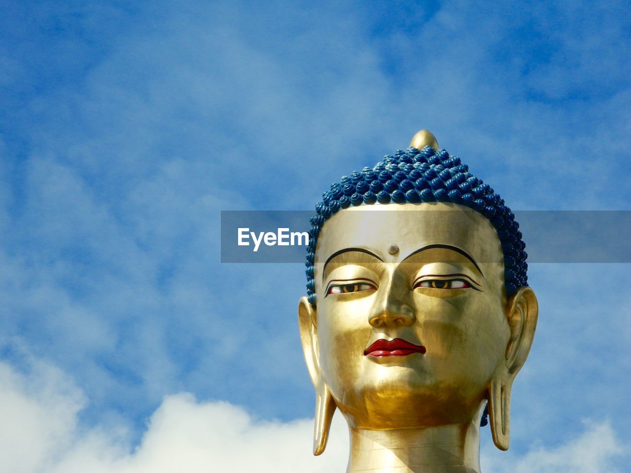 CLOSE-UP OF BUDDHA STATUE AGAINST SKY