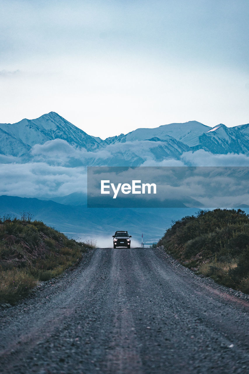 View of car on dirt road against mountain