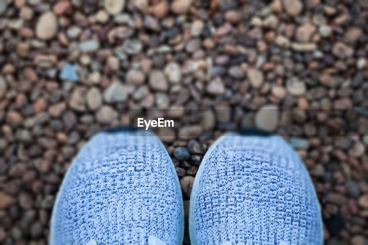 Directly above shot of shoes on pebble stones