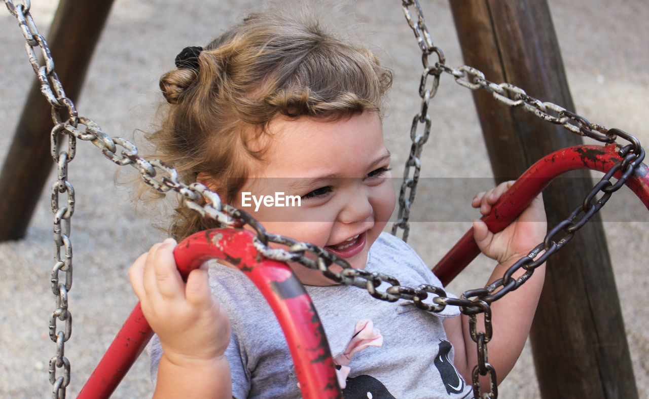 Close-up of cheerful girl on swing