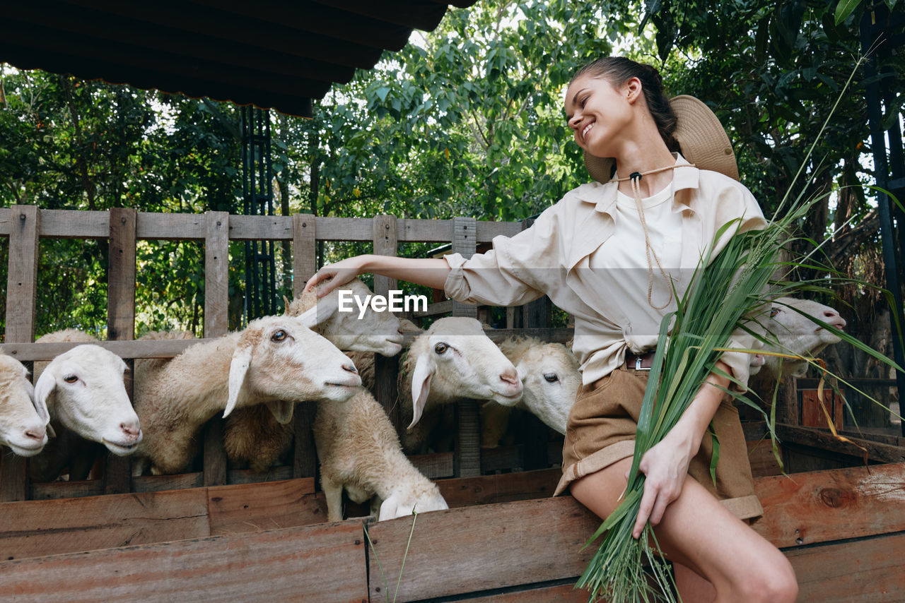 portrait of smiling young woman with goat in farm