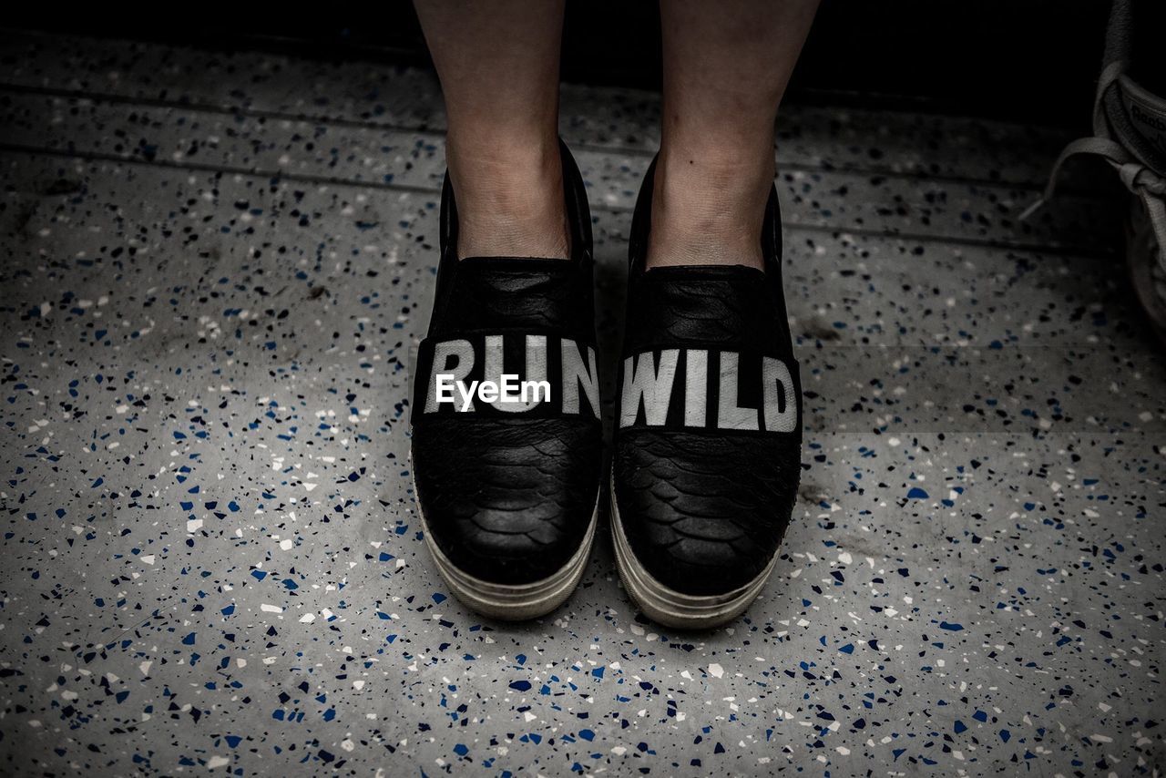 Low section of man wearing shoes with text on floor