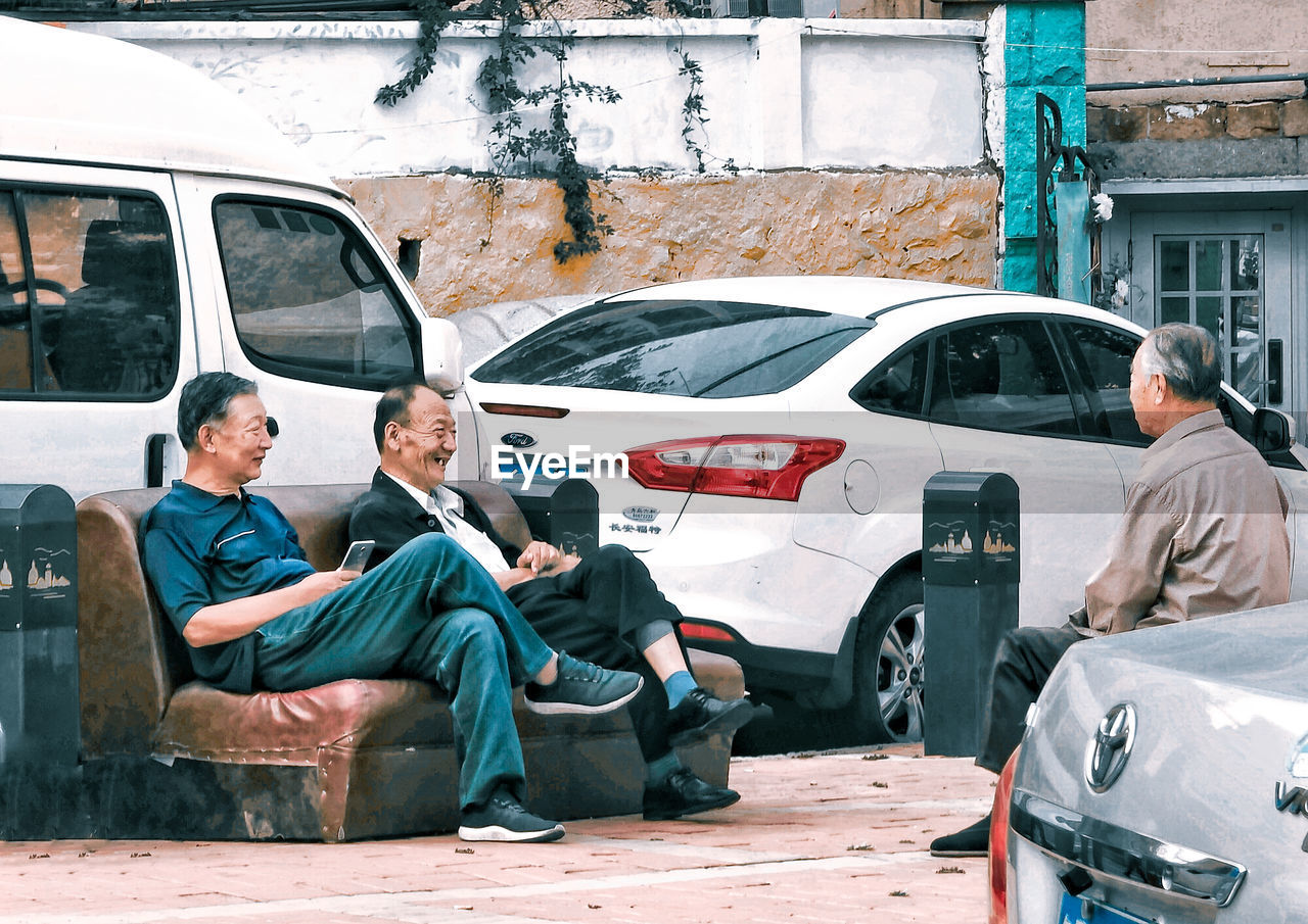 PEOPLE SITTING IN CAR BY BUILDING