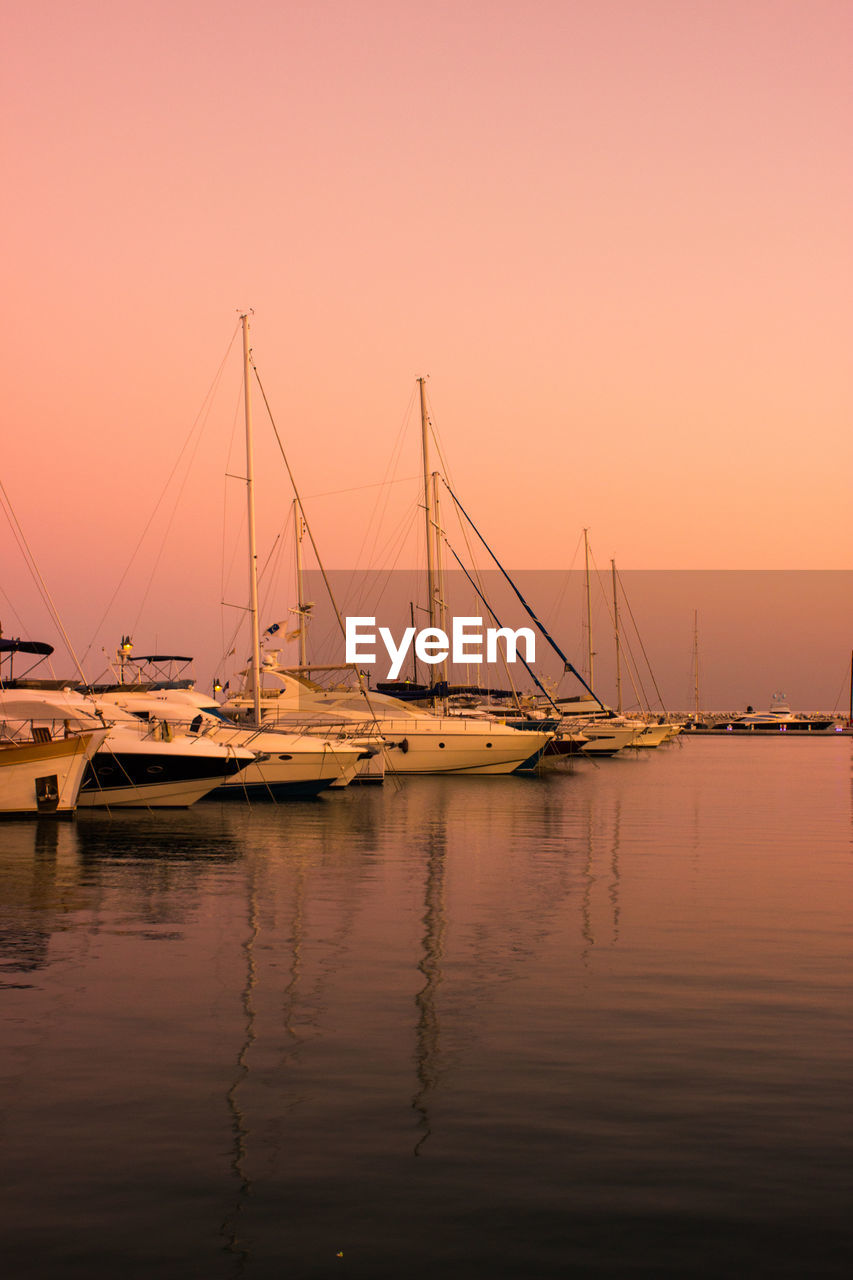 Boats moored on sea against clear sky during sunset