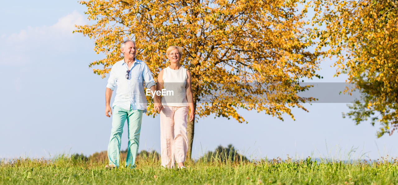 Full length of couple walking on land against sky