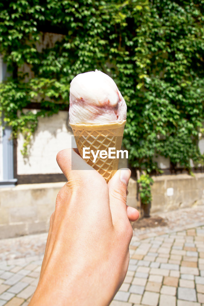 Cropped image of hand holding ice cream cones on street