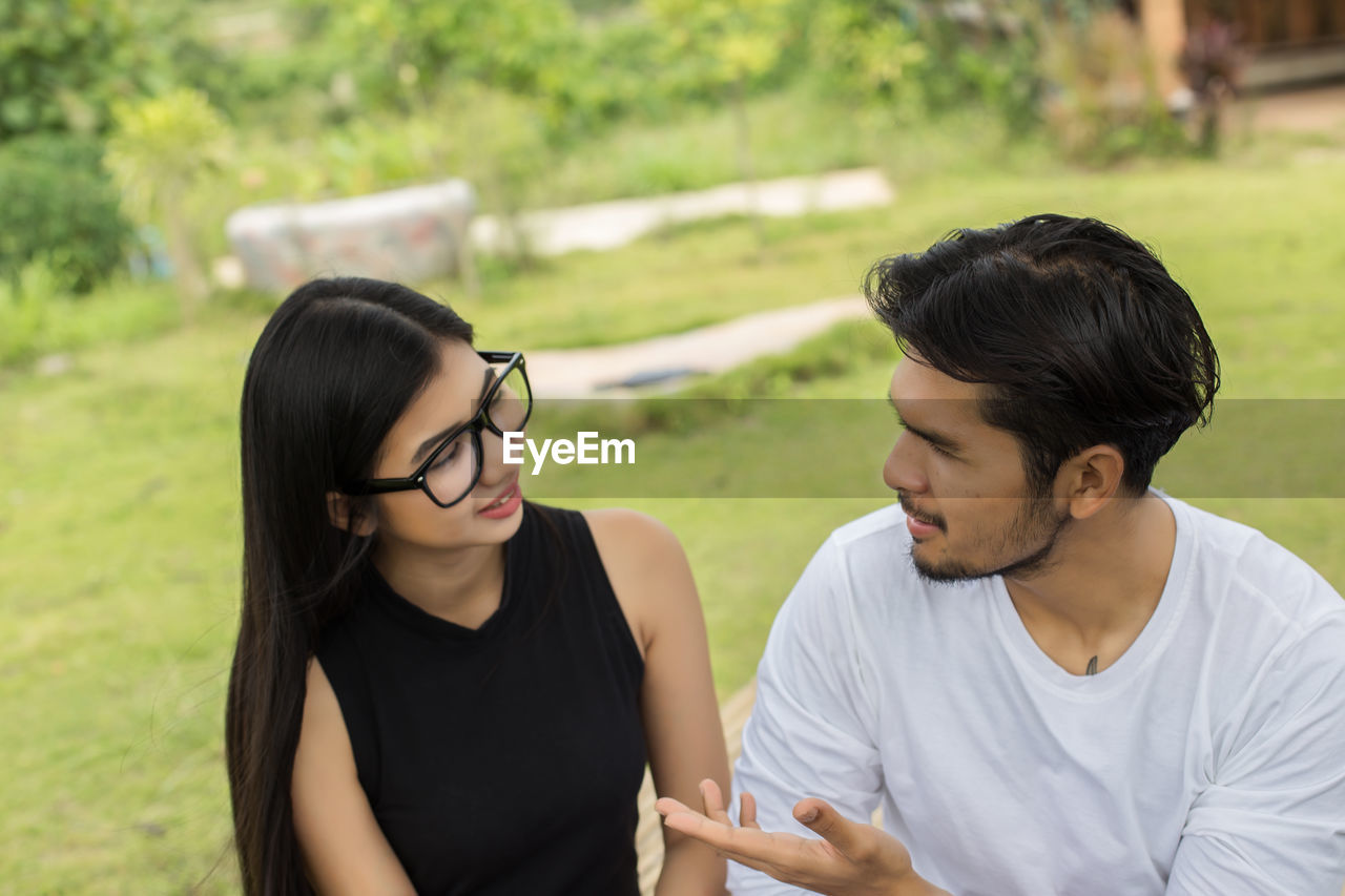 YOUNG COUPLE LOOKING AT SMART PHONE OUTDOORS