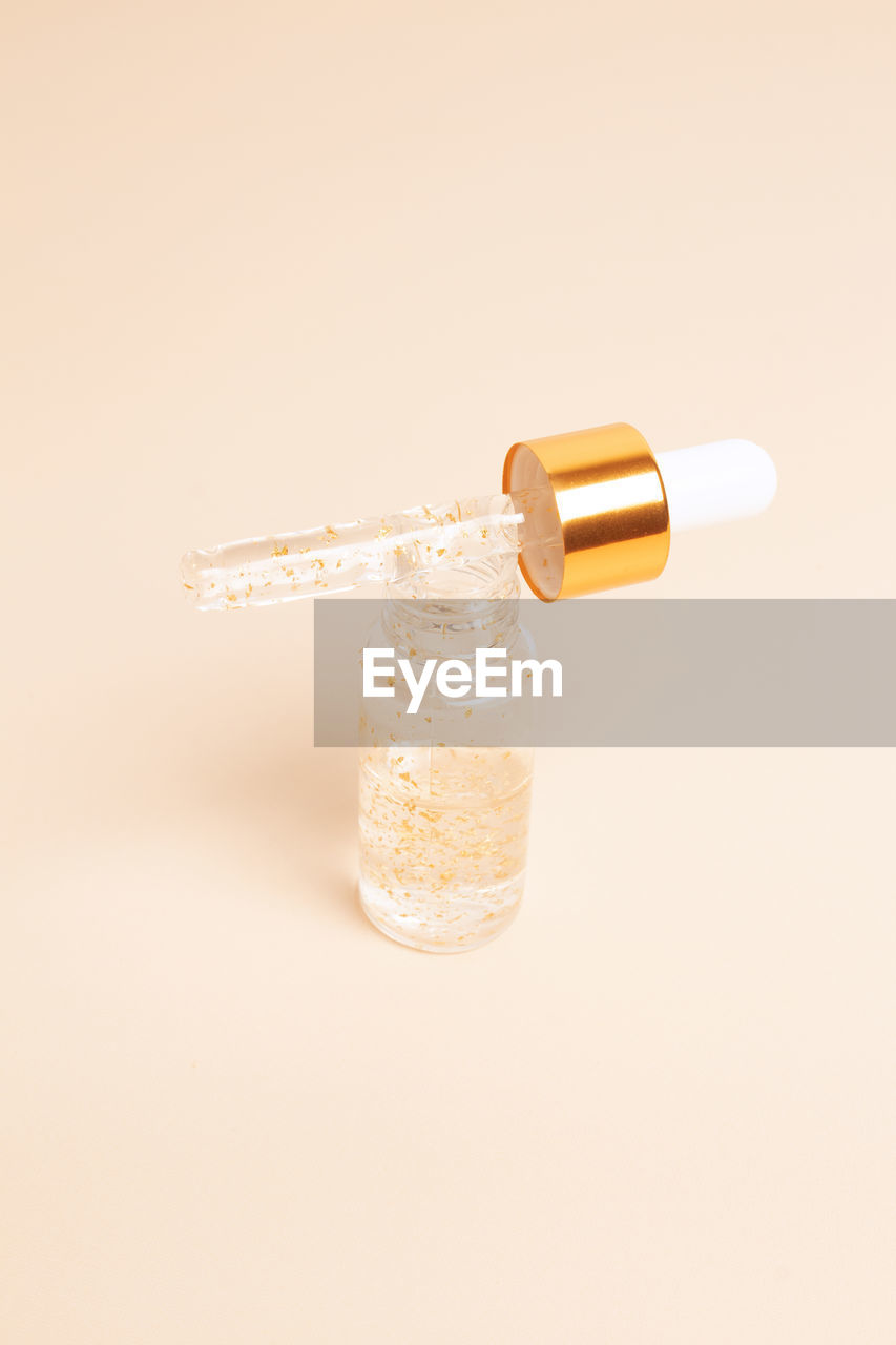 Dropping serum gold collagen moisturizer of face soft light background. protector skin treatment 