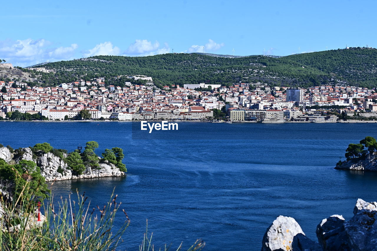 water, architecture, sea, building exterior, built structure, coast, nature, building, sky, city, land, body of water, shore, travel destinations, vacation, mountain, bay, beach, no people, town, residential district, day, house, scenics - nature, travel, beauty in nature, blue, plant, coastline, nautical vessel, cityscape, outdoors, transportation, landscape, tourism, harbor, environment, ocean, clear sky, high angle view, village, sunlight, sunny