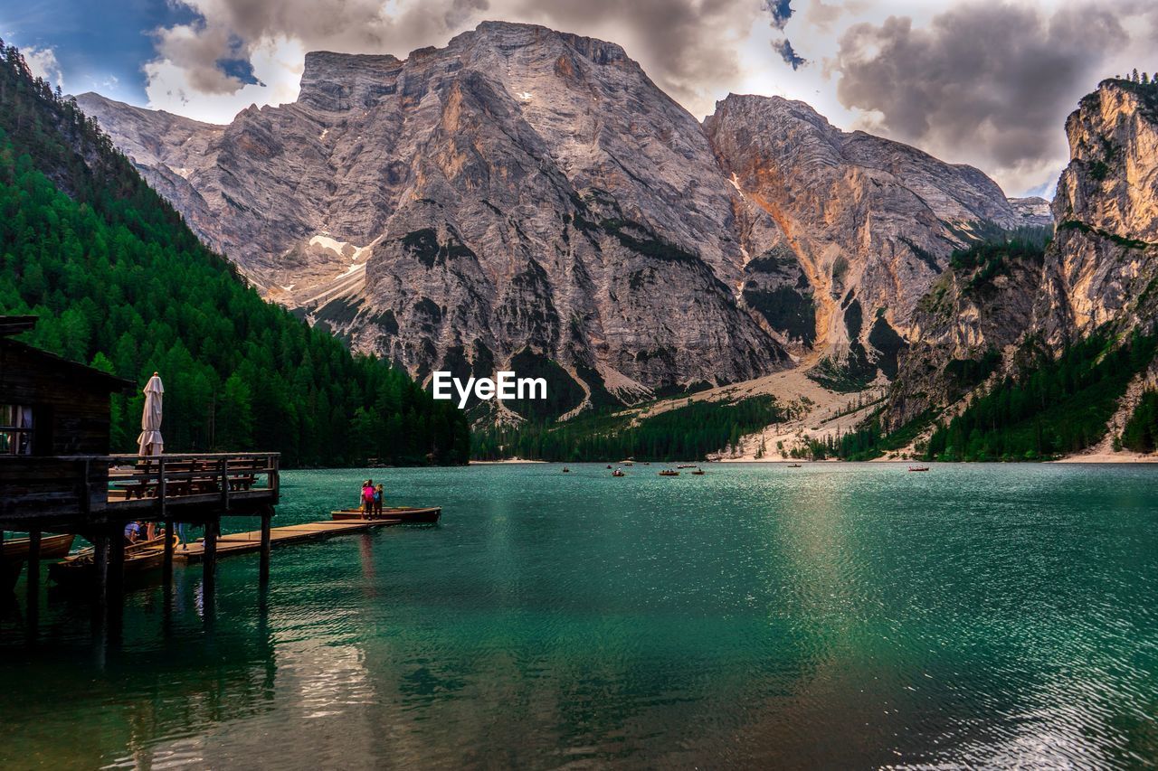 Scenic view of lake and mountains. people walking on water, watching boats float.