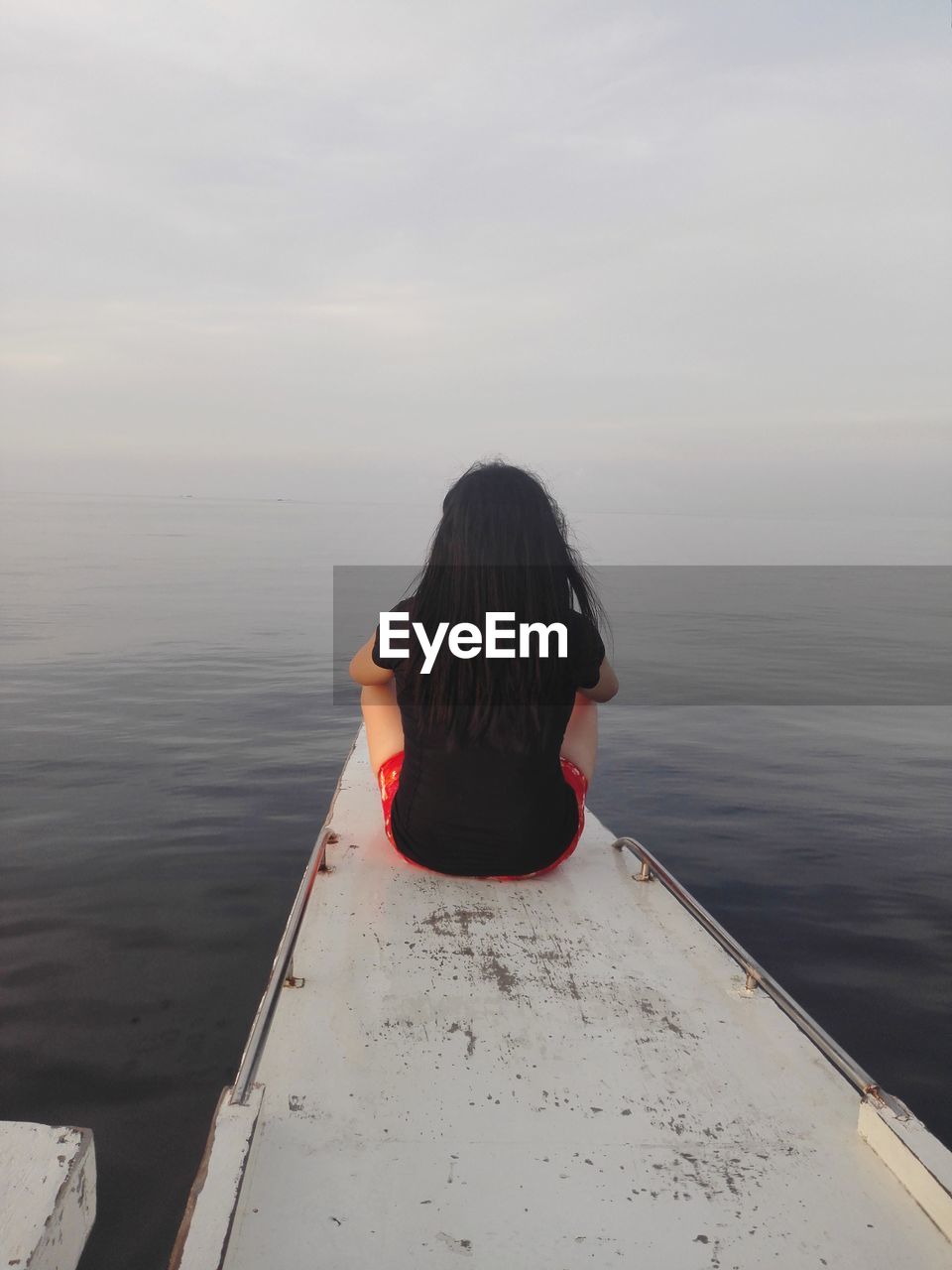 Rear view of woman sitting on boat over sea against sky