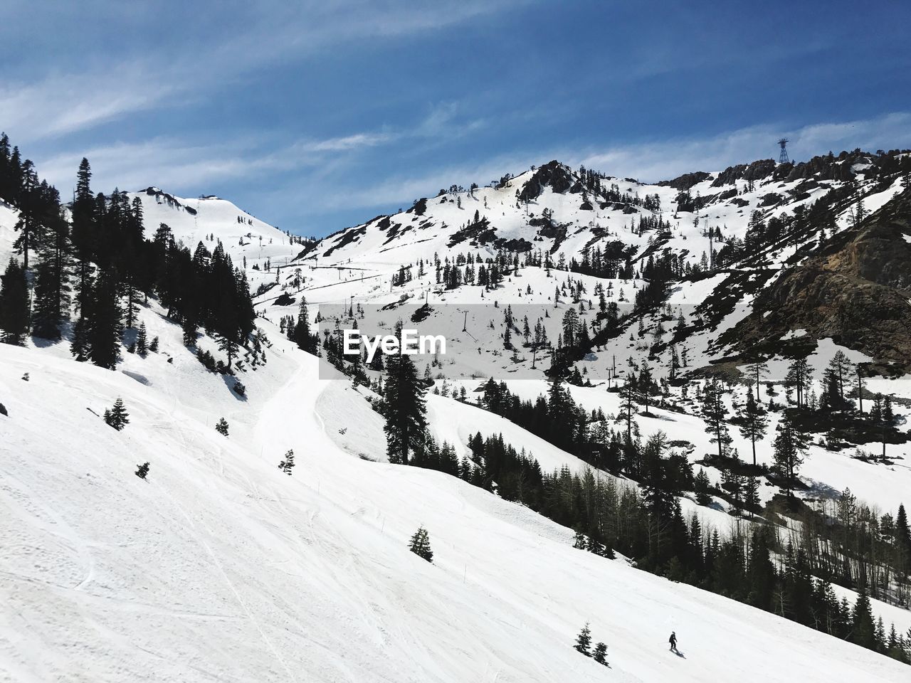 PANORAMIC VIEW OF PEOPLE SKIING ON SNOWCAPPED MOUNTAIN AGAINST SKY