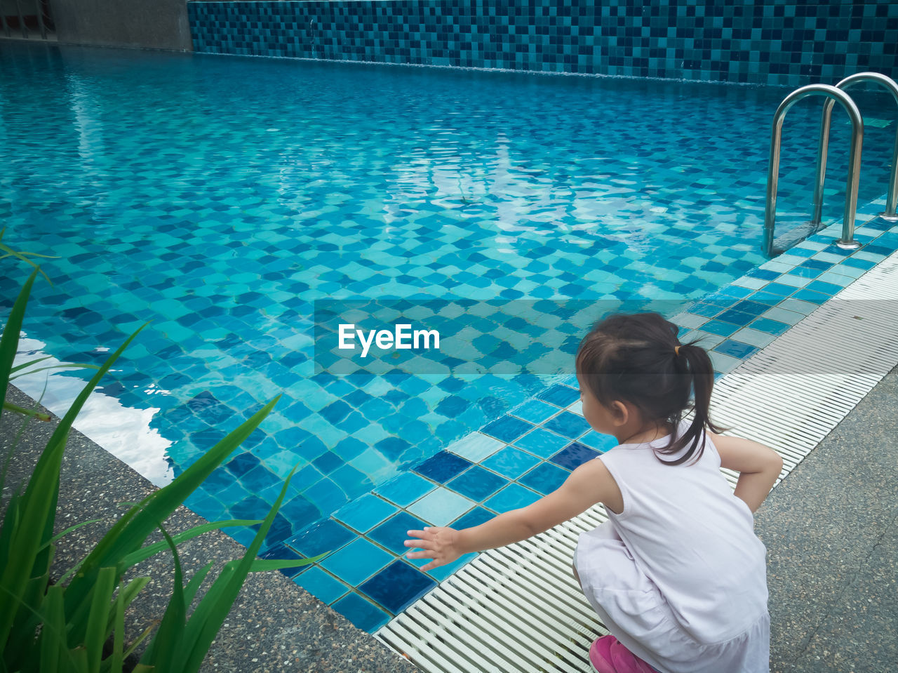 Little asian toddler baby have a fun with a splash near swimming pool