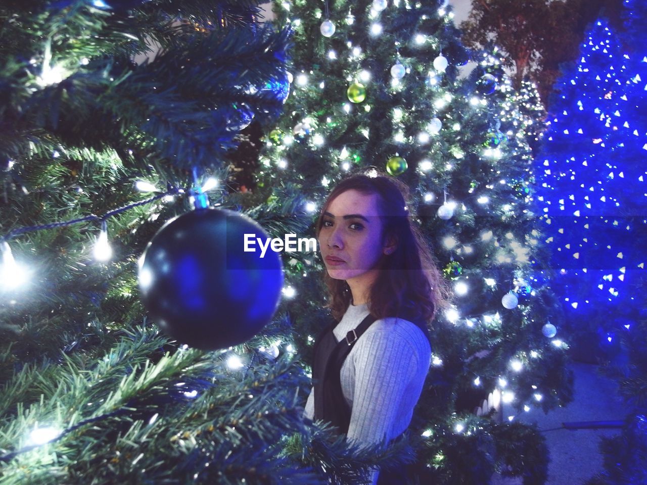 Portrait of woman standing amidst christmas tree