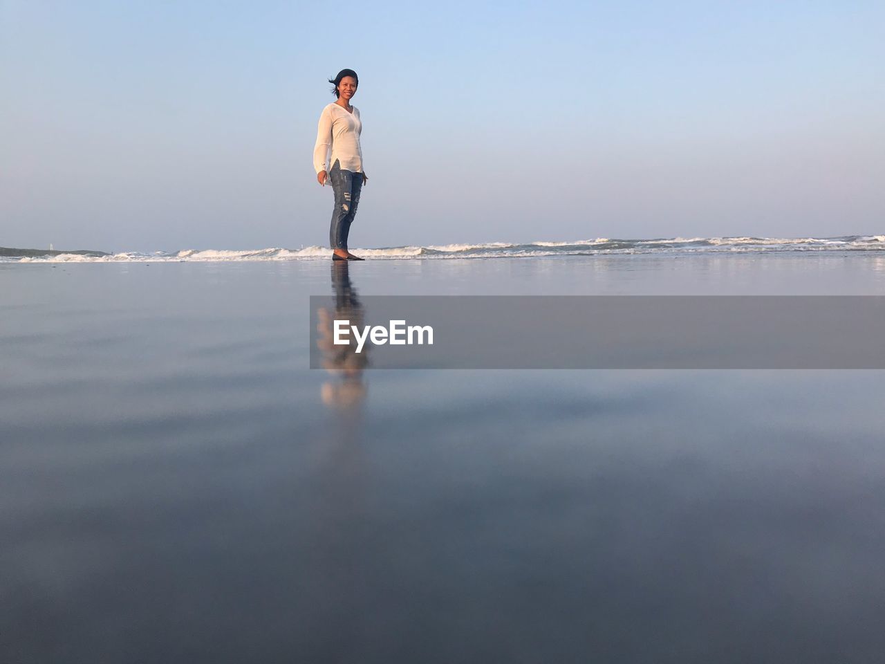 Portrait of woman standing at beach against clear sky