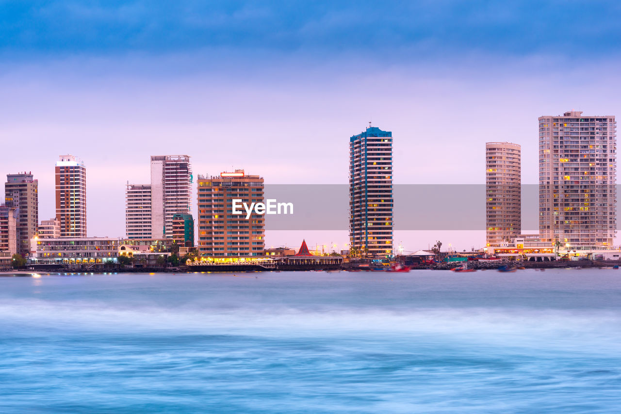 SEA AND BUILDINGS AGAINST SKY IN CITY