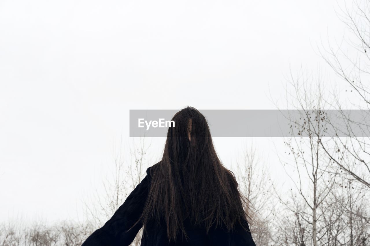  woman with long hair standing against clear sky in winter