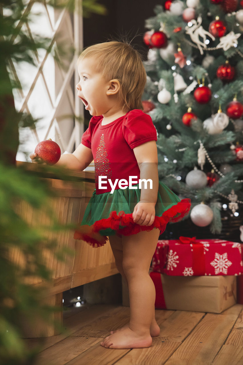 portrait of cute girl playing with christmas tree at home