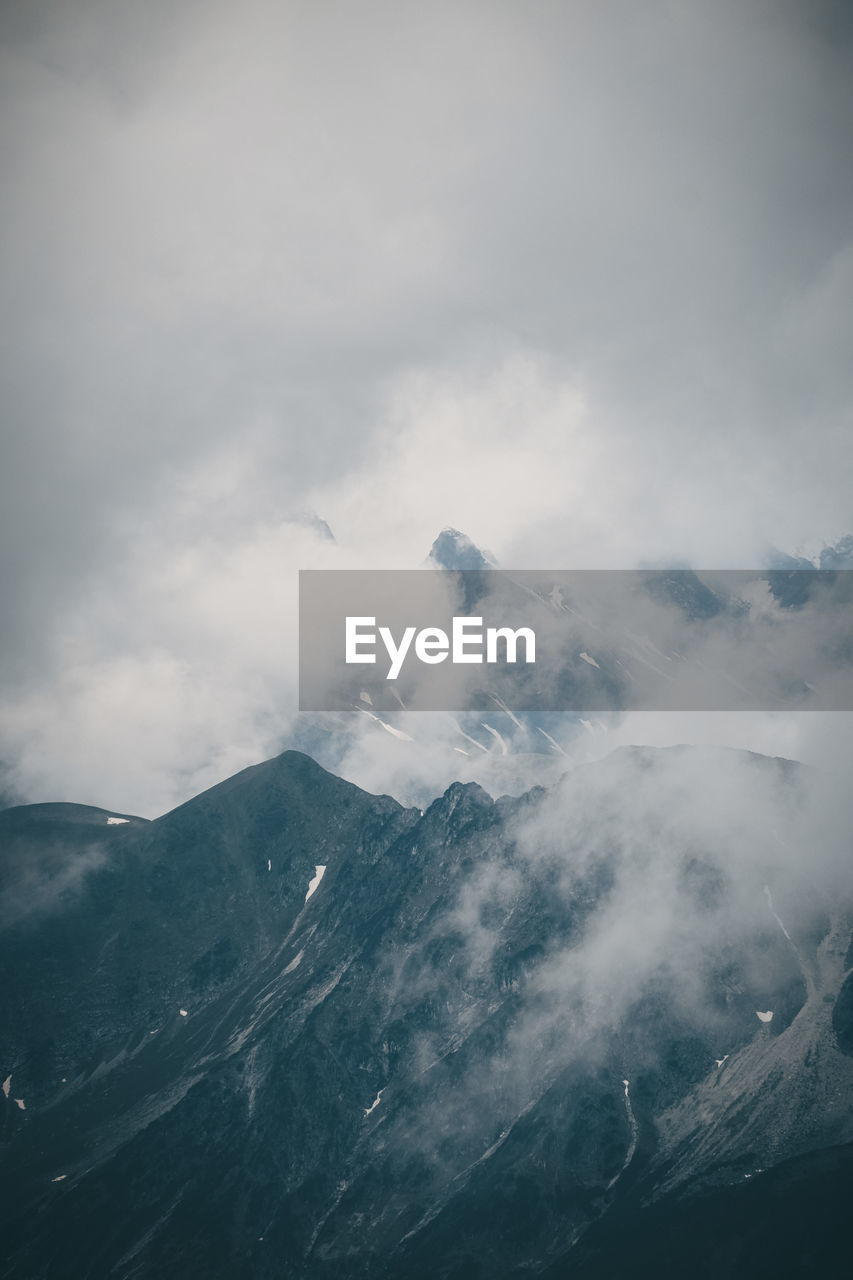 Scenic view of high mountains surrounded by clouds