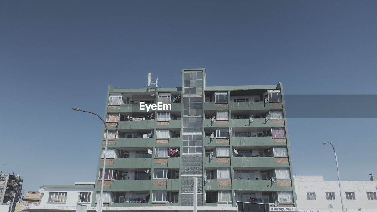 LOW ANGLE VIEW OF RESIDENTIAL BUILDING AGAINST CLEAR SKY