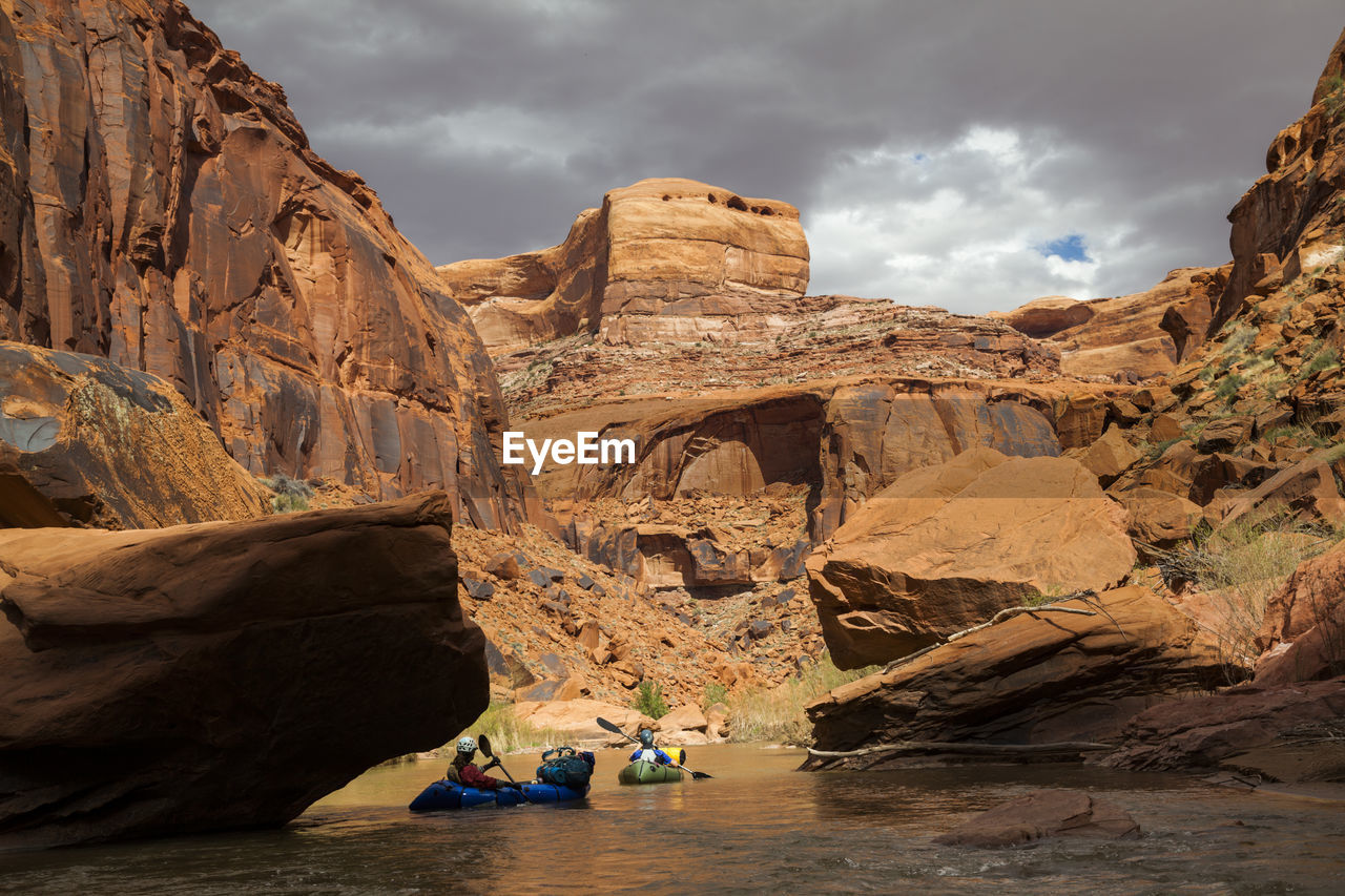 People paddle packrafts below high cliffs on escalante river, utah