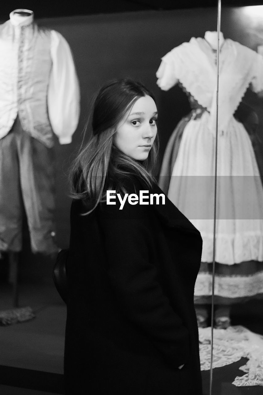 Portrait of woman standing against store