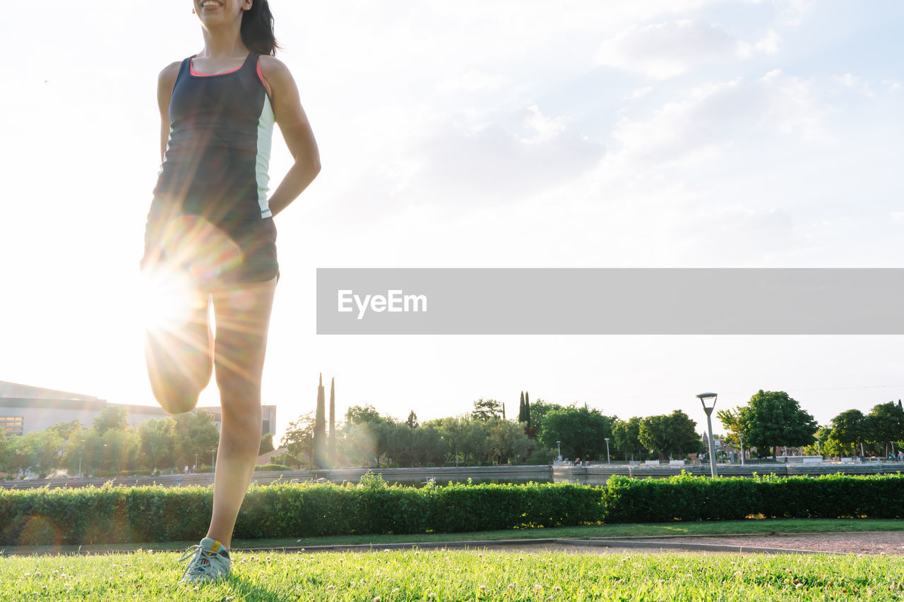 WOMAN STANDING ON FIELD AGAINST SKY