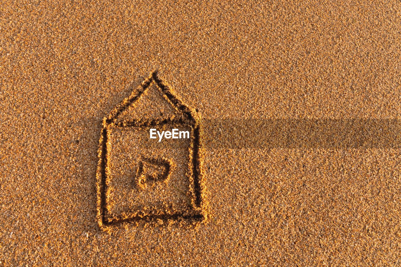 The house is drawn on the sand. drawing of a house on the beach, safety and relaxation concept