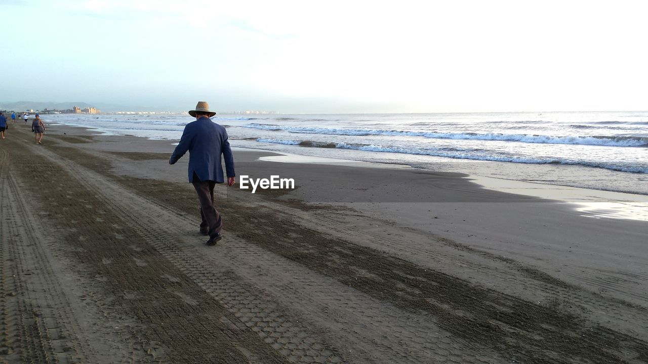 Rear view of man walking on beach