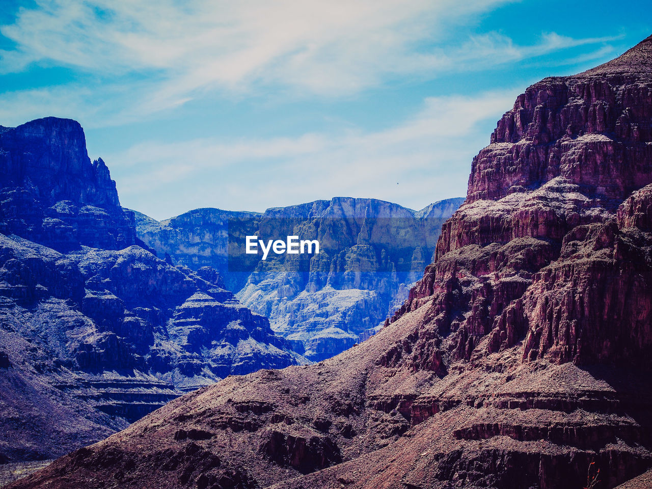 Rocky mountains against cloudy sky on sunny day at grand canyon national park