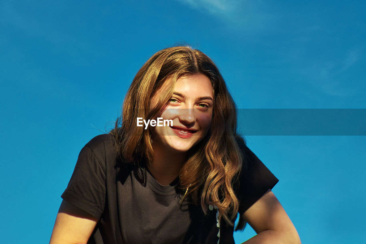 Portrait of smiling girl against blue sky