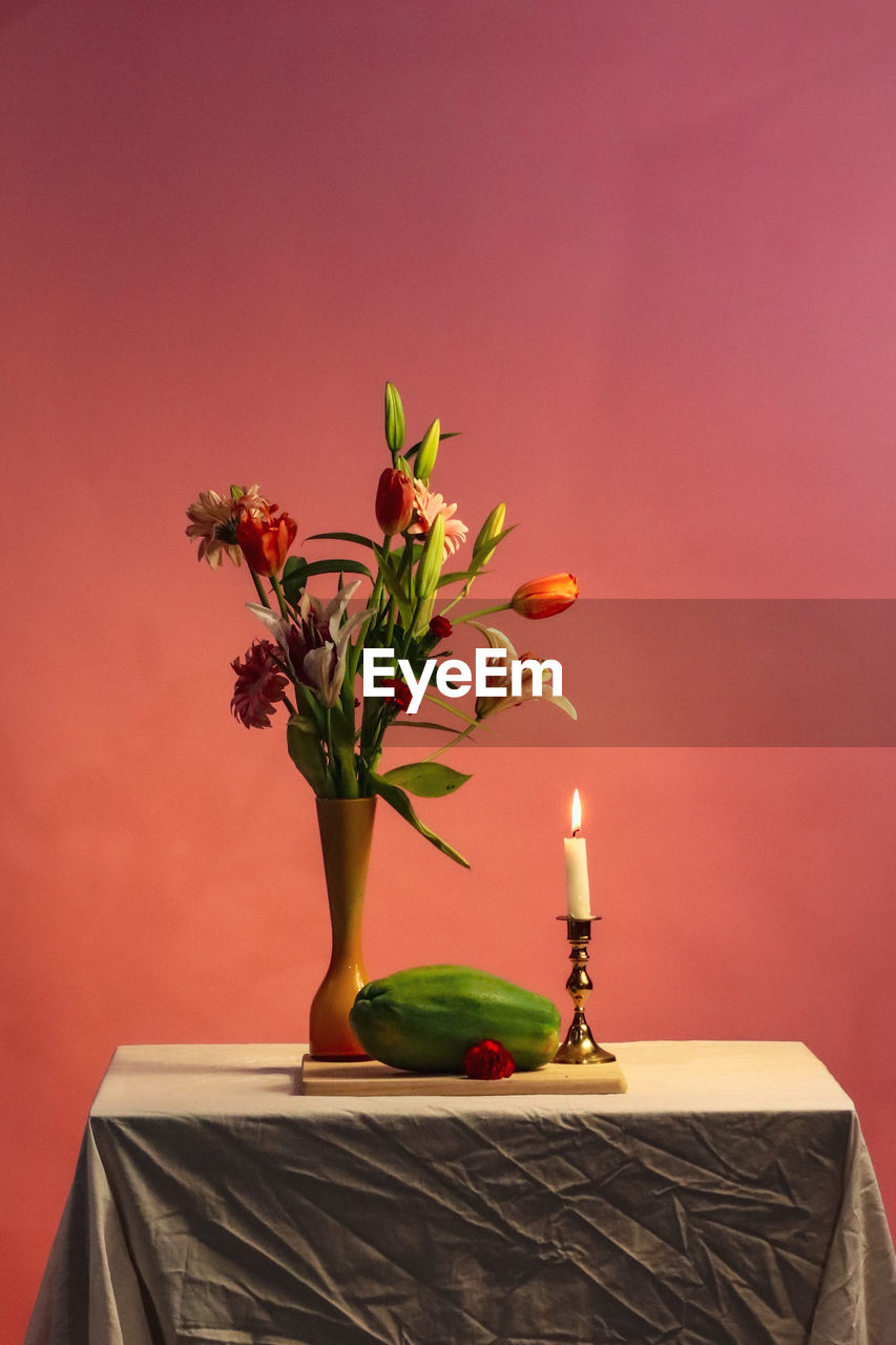 Close-up of red flower vase on table against wall