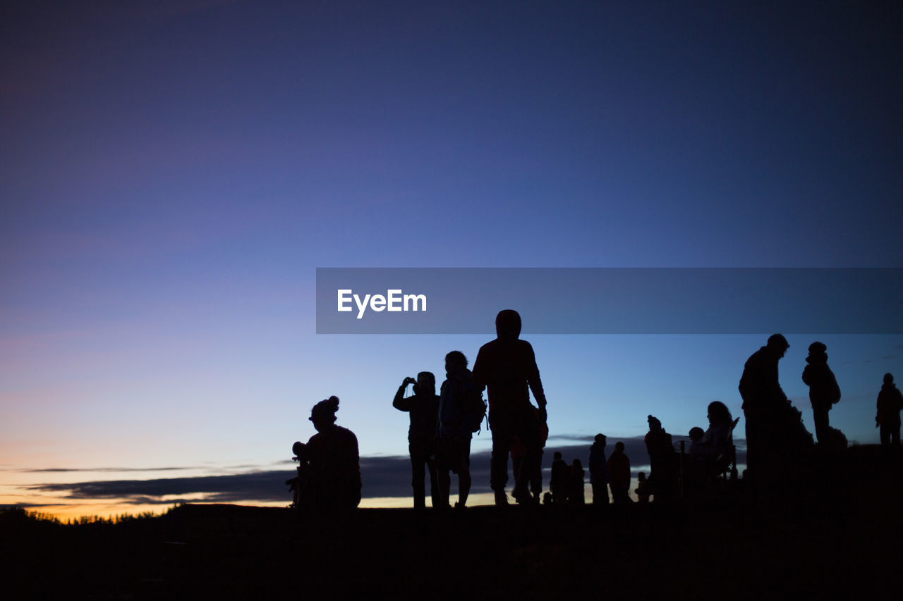 Silhouette people against clear blue sky during sunset