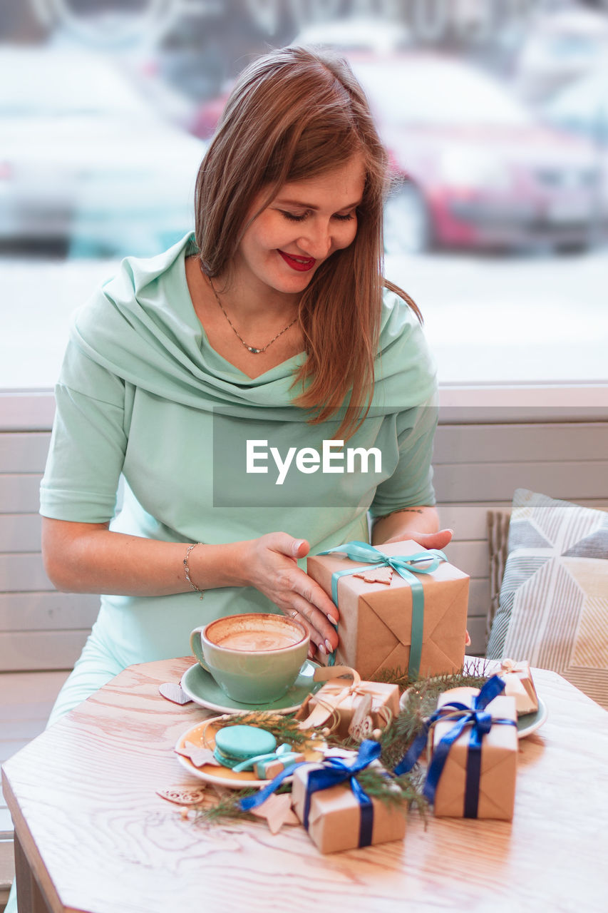 Young smiling pregnant woman in cafe with cup of coffee and christmas gifts. pregnant lifestyle.