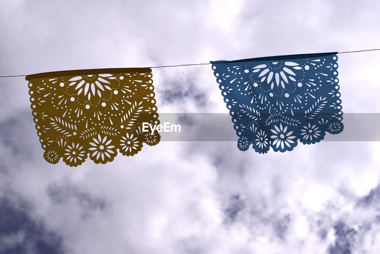 Low angle view of crochet flags hanging against sky