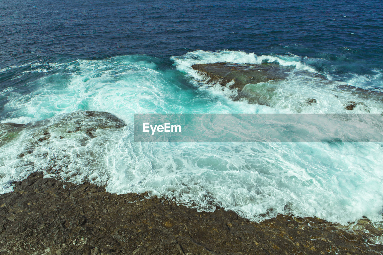 High angle view of surf on shore at beach