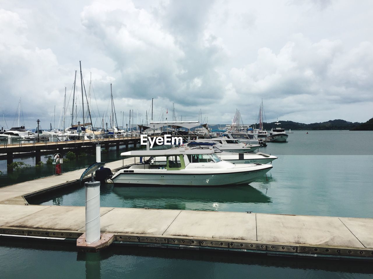 BOATS MOORED ON HARBOR AGAINST SKY