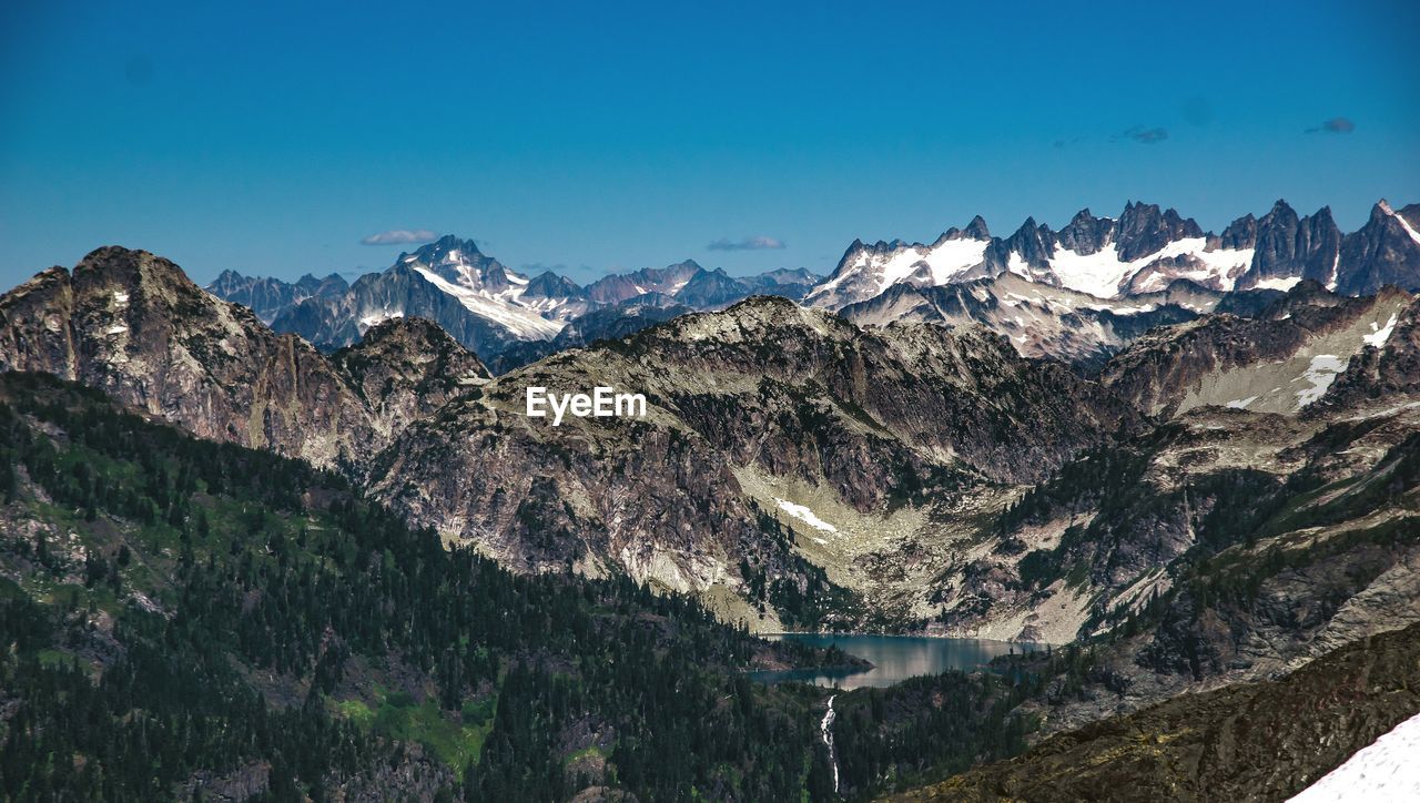 Scenic view of snow covered mountains against blue sky