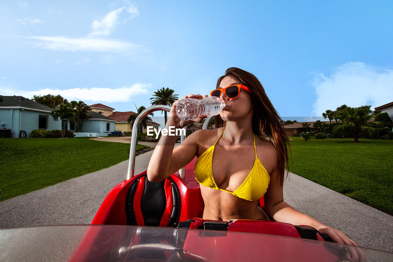 Beautiful woman drinking water while sitting in car