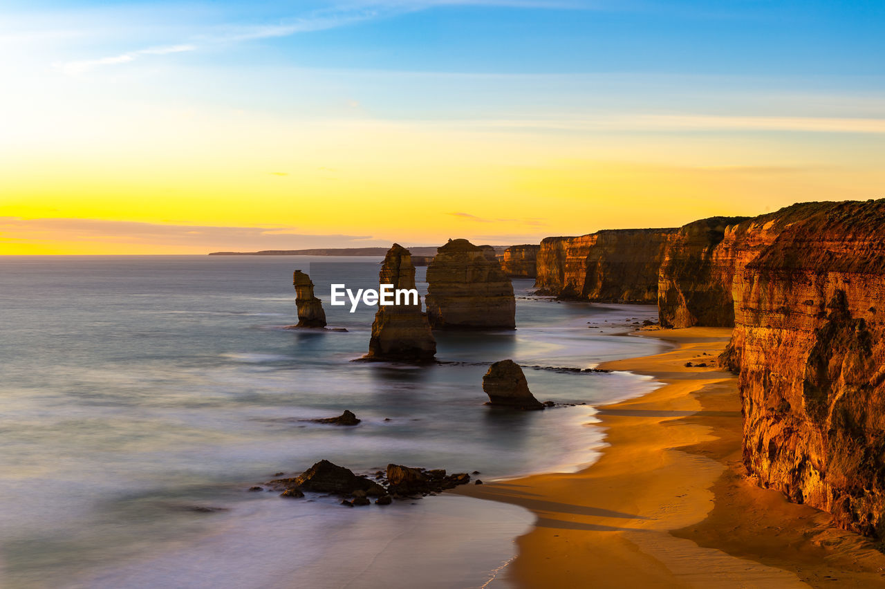 ROCKS ON SEA SHORE AGAINST SKY DURING SUNSET